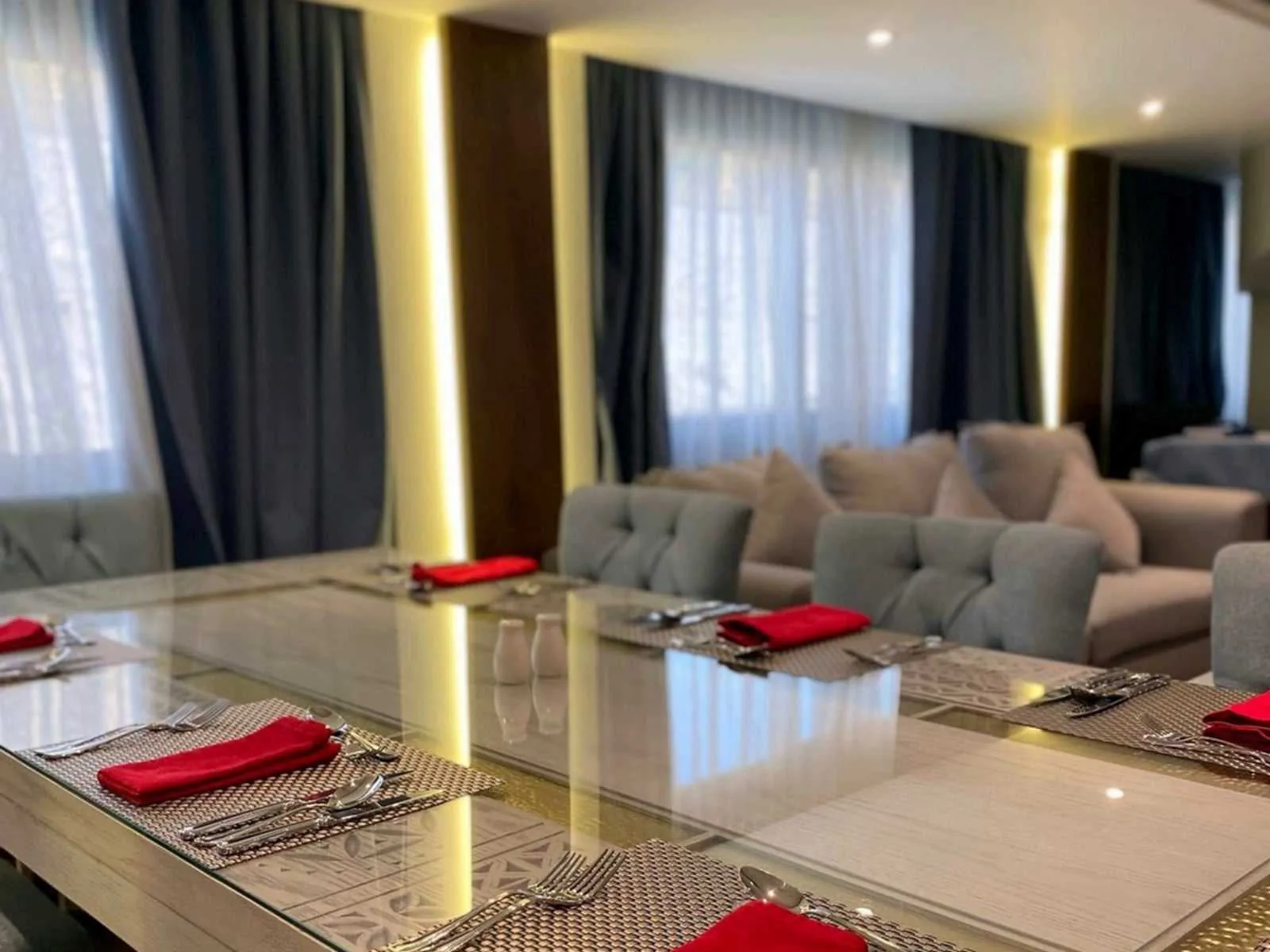 Una mesa de comedor con servilletas rojas en la dahabiya Iris, con sofás grises detrás