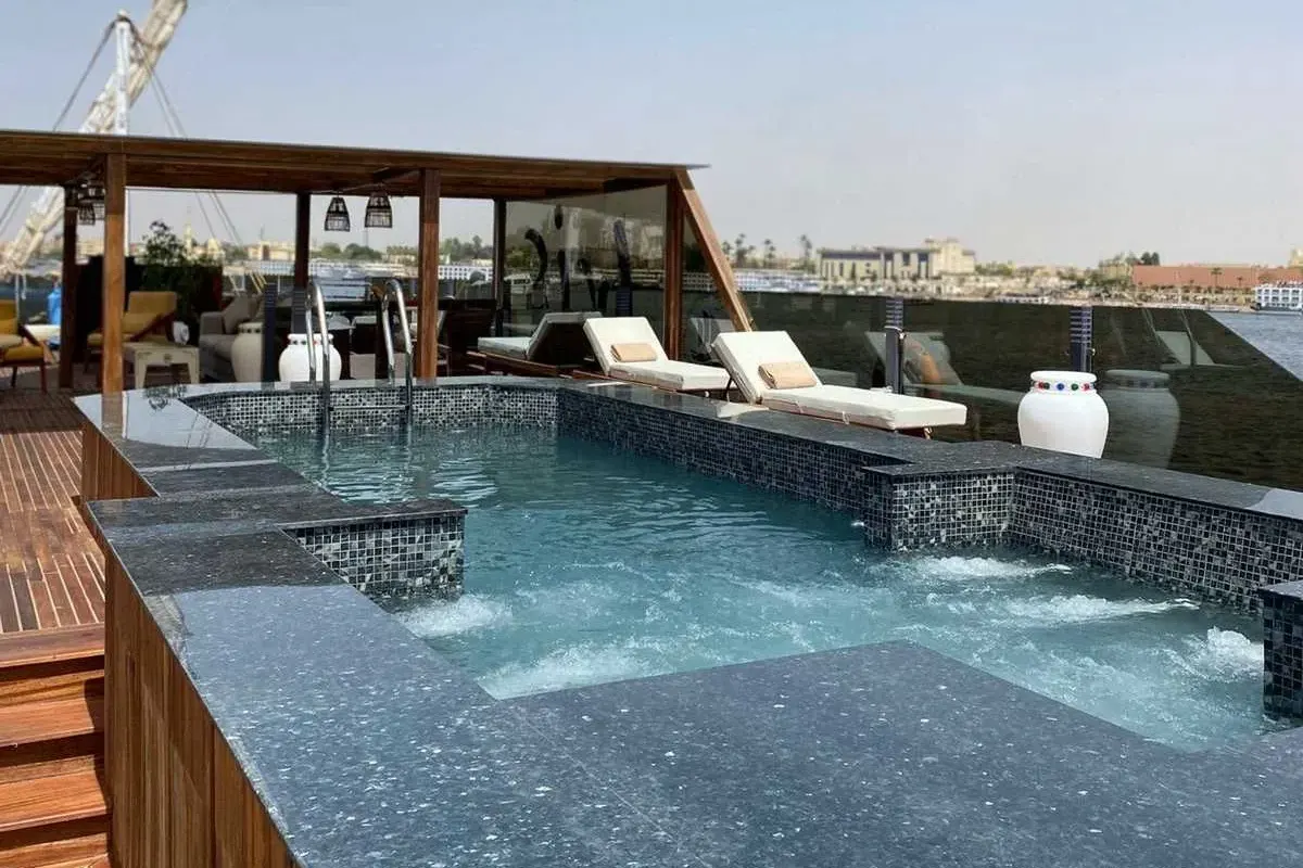 La piscina de la cubierta solárium de la dahabiya Iris, con tumbonas a su lado bajo un toldo