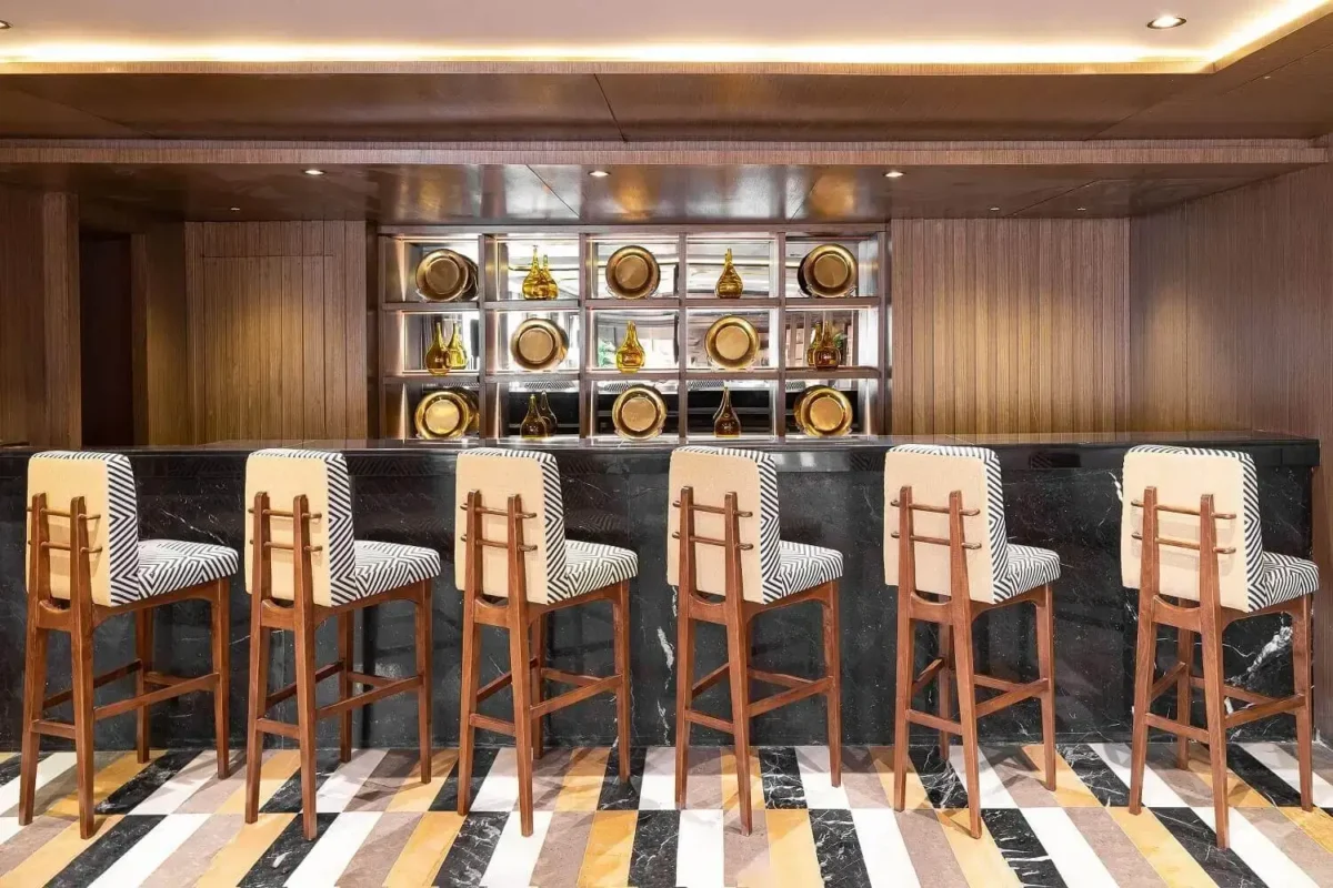A row of high stools at the marble bar counter of the MS Jaz Viceroy Nile cruise, shelves of glassware behind