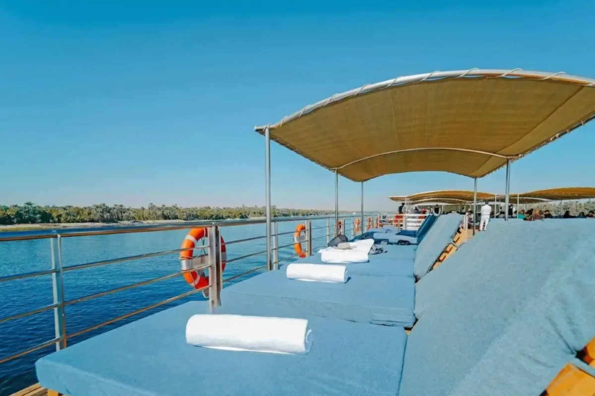 Blue loungers with rolled towels under the shade canopy of the MS Miriam Nile cruise sun deck, the river alongside