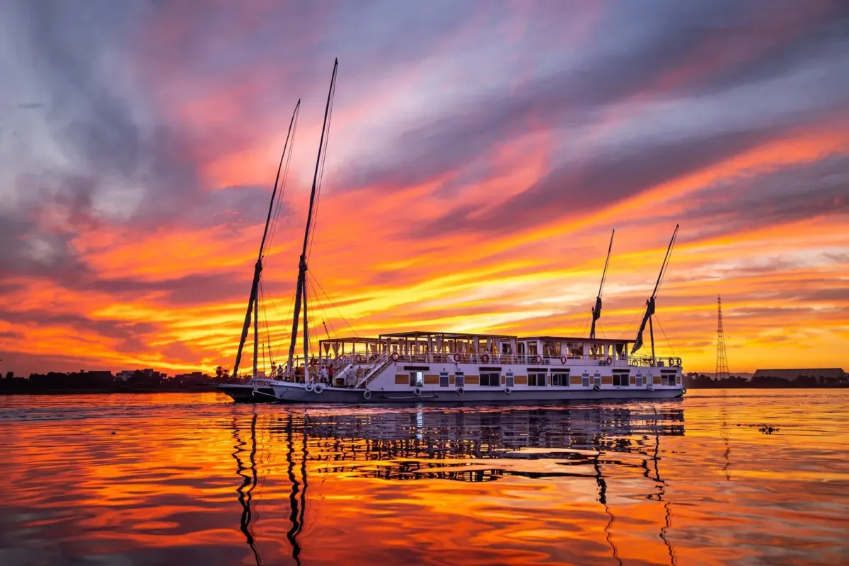 Die Dahabiya Princess Cleopatra vor Anker auf dem Nil unter einem rot-orangefarbenen Abendhimmel