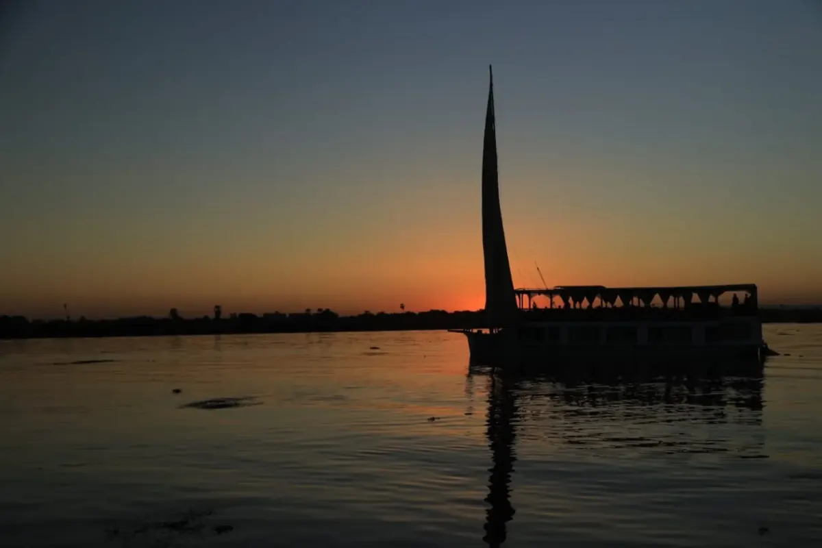 La dahabiya Queen Nefer en silueta sobre el Nilo al atardecer