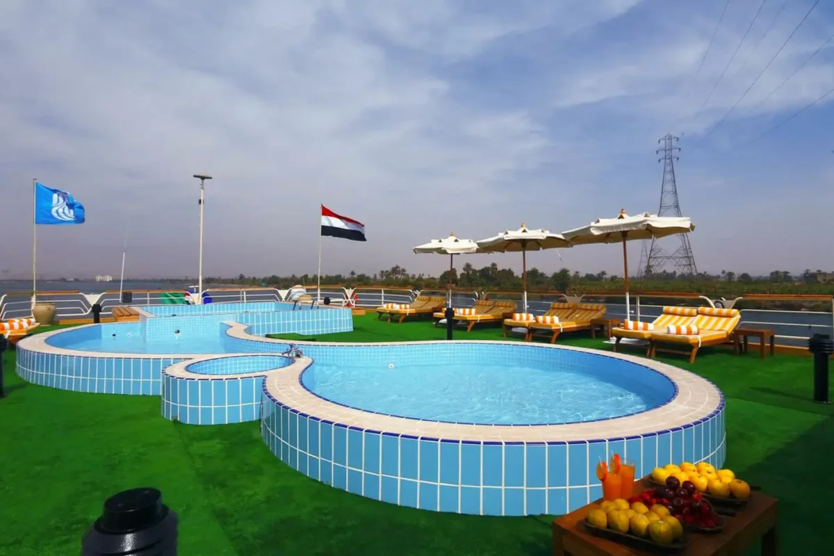 The swimming pool and round jacuzzi on the Sonesta Nile Goddess Nile cruise sun deck, an Egyptian flag flying above