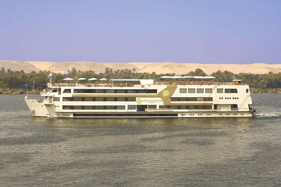 The Sonesta Nile Goddess Nile cruise ship broadside on the Nile below a pale sand escarpment