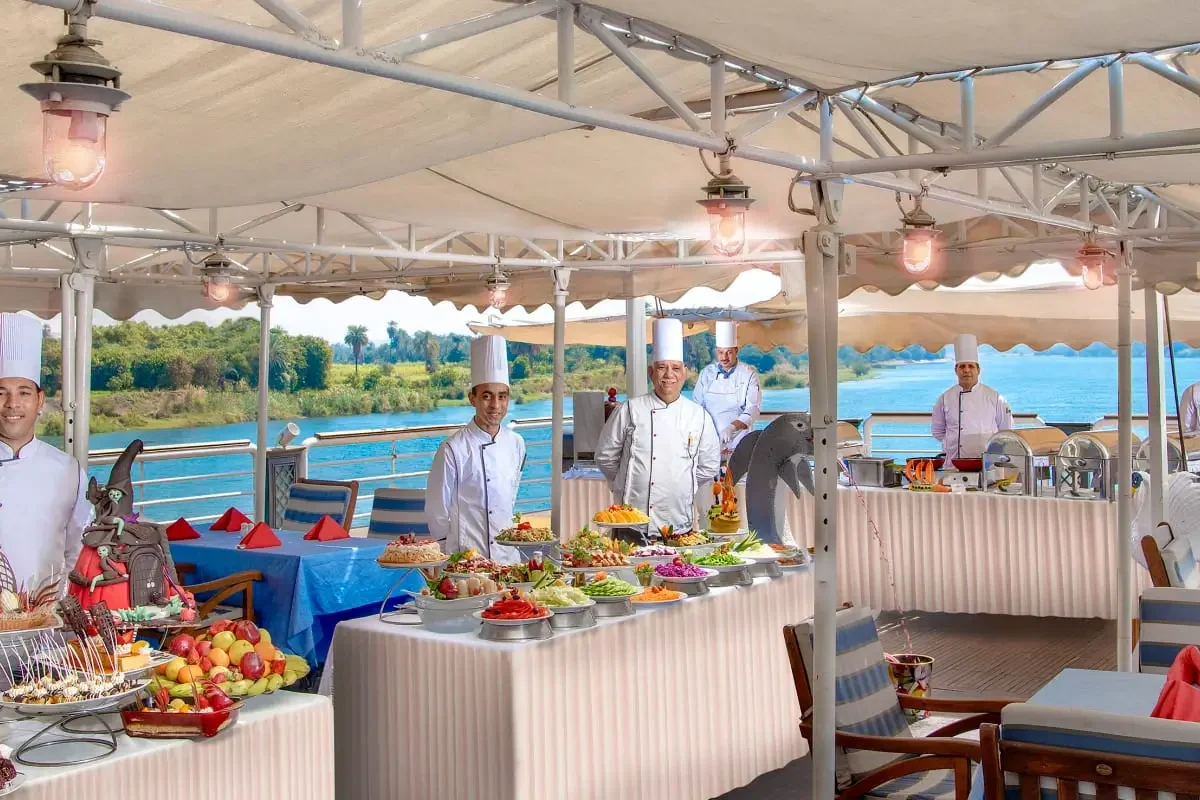 Chefs behind a buffet laid out on the shaded deck of the Sonesta St. George I Nile cruise, tables set alongside