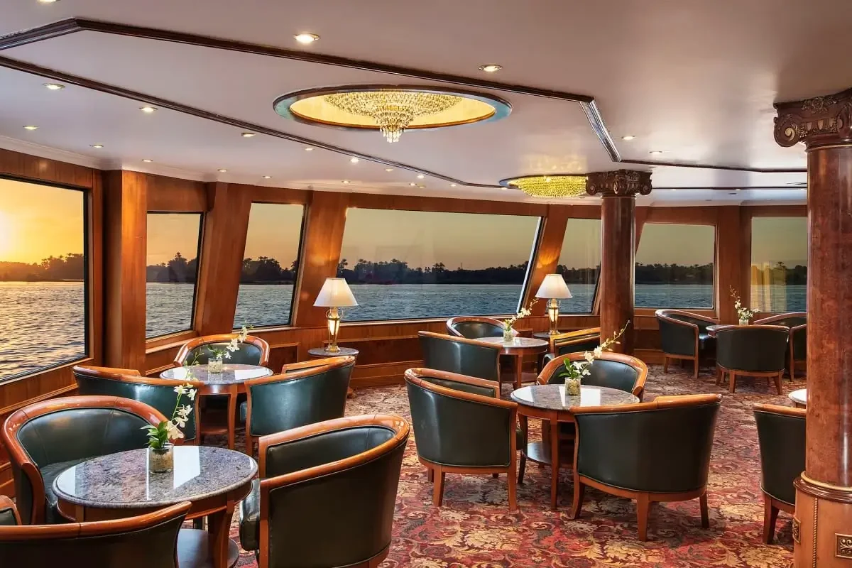 The lounge on the Sonesta St. George I Nile cruise, leather tub chairs at the windows with the sun setting over the Nile