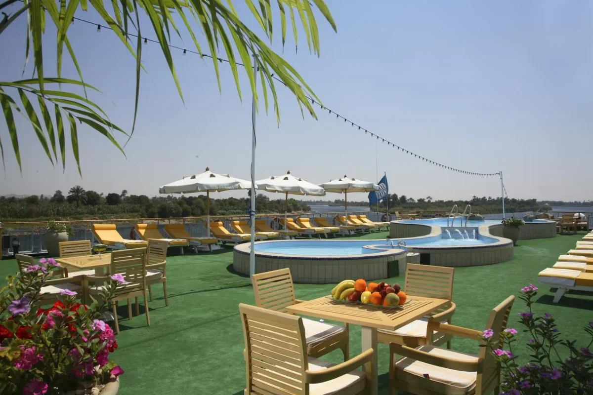 The pool on the Sonesta Star Goddess Nile cruise sun deck, timber tables and loungers on green lawn around it