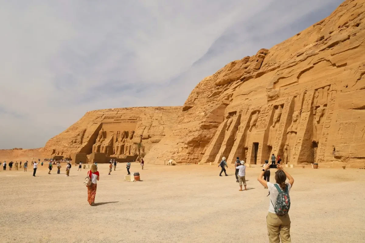 The Great Temple of Ramses II and the Small Temple of Nefertari carved into the cliff at Abu Simbel, visitors crossing the forecourt between them