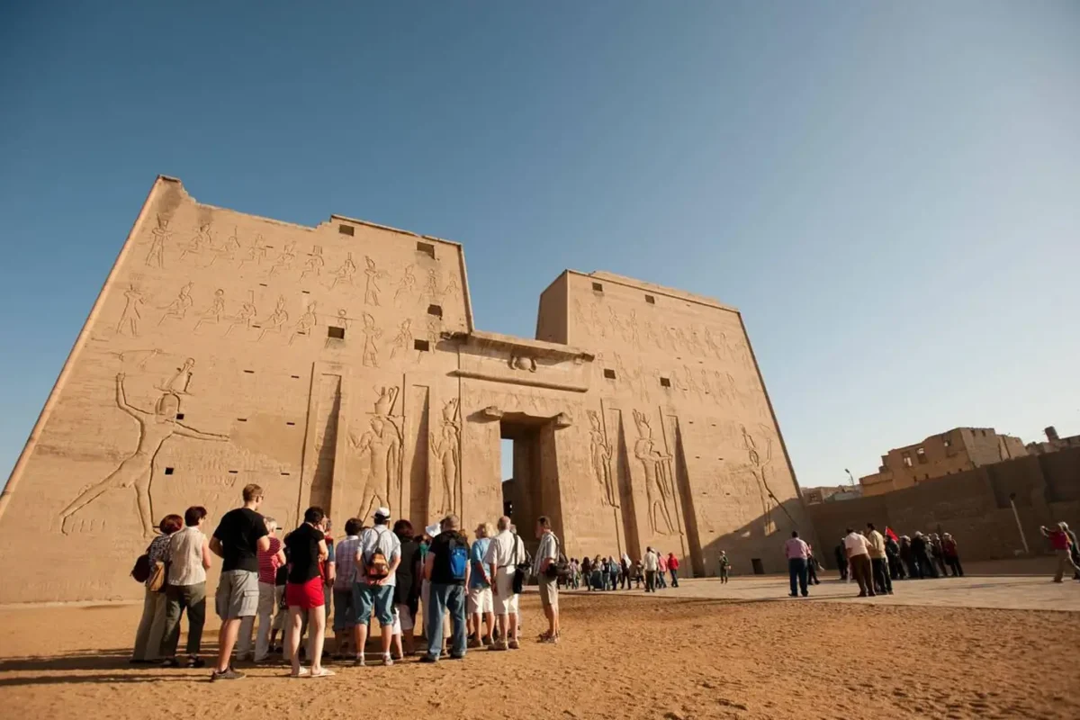 A line of visitors reading the reliefs on the great pylon of the Temple of Horus at Edfu