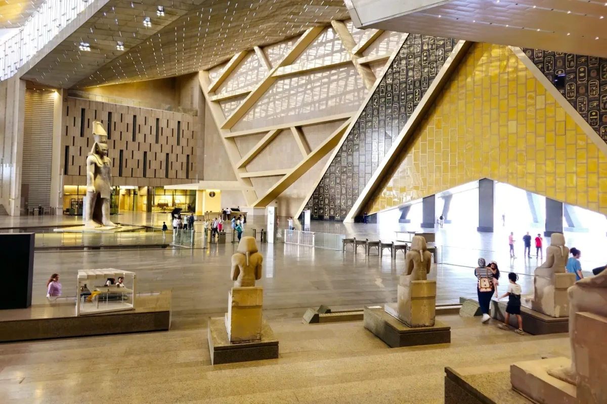 Statues lining the grand staircase of the Grand Egyptian Museum, daylight falling through the triangular openings