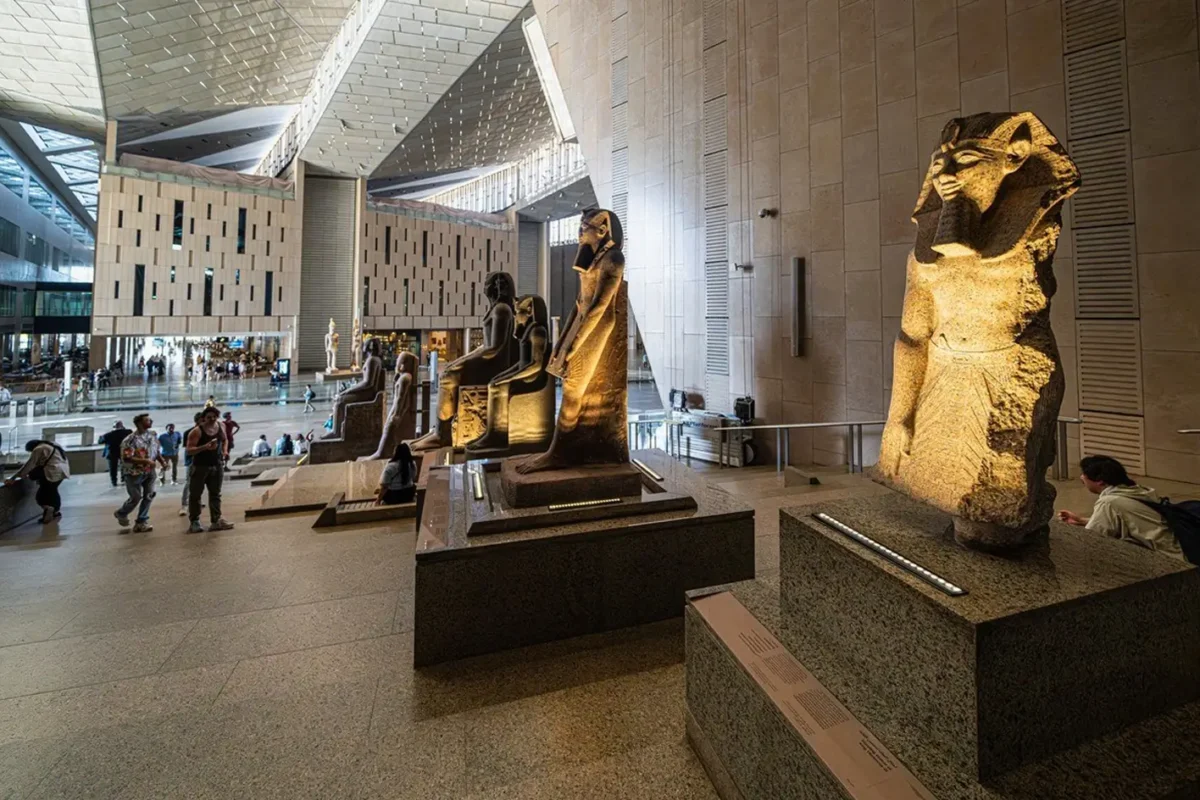 Visitors photographing royal statues set along the staircase of the Grand Egyptian Museum