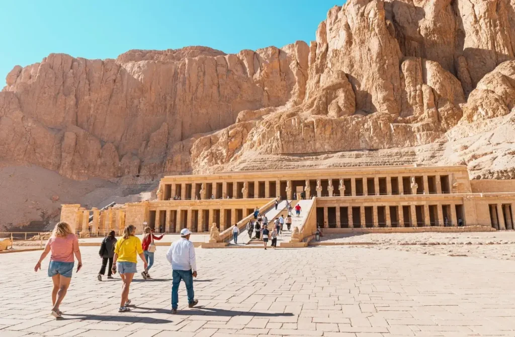 Visitors crossing the forecourt of the Temple of Hatshepsut, the limestone cliffs of Deir el-Bahari rising behind it