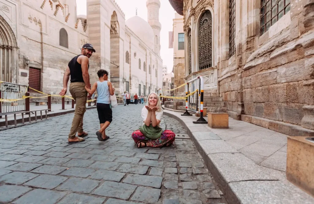 Visitors on the stone-paved Al-Muizz Street beside Khan el-Khalili, historic mosque façades running down one side