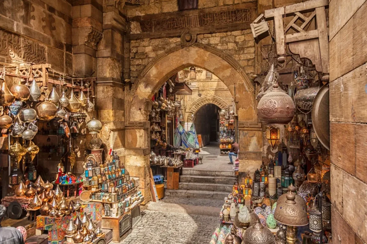 Copperware and hanging lanterns filling a stone archway in the Khan el-Khalili bazaar in Cairo