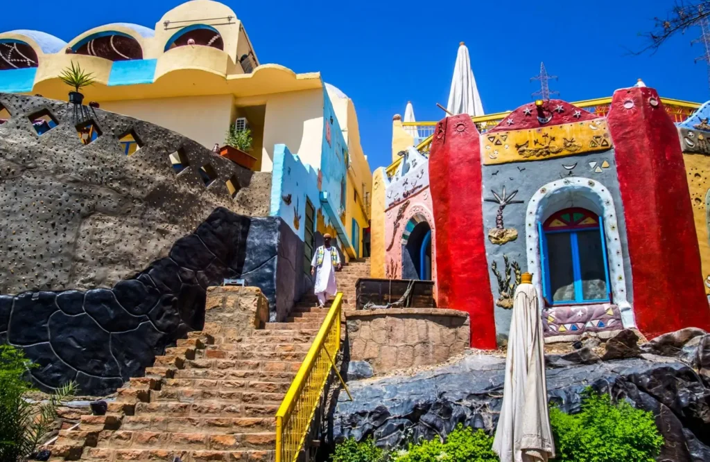 Brightly painted Nubian houses climbing a rocky slope above stone steps in a village near Aswan