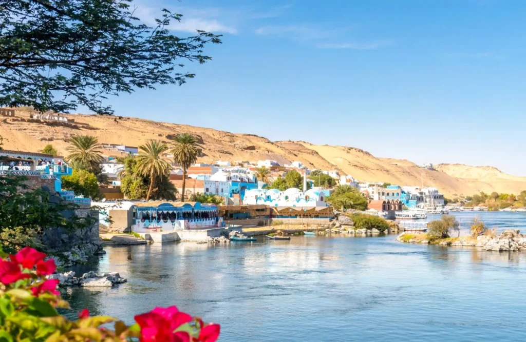 A Nubian village of blue and white houses along the Nile at Aswan, a sand ridge rising behind it