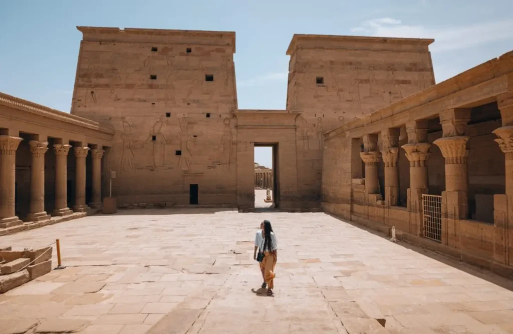 A visitor crossing the first court of the Temple of Philae towards the great pylon