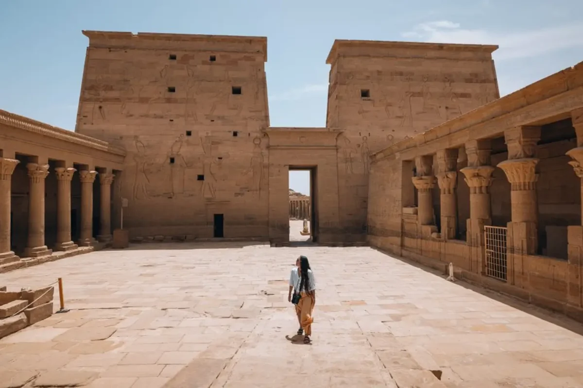 A visitor crossing the first court of the Temple of Philae towards the great pylon
