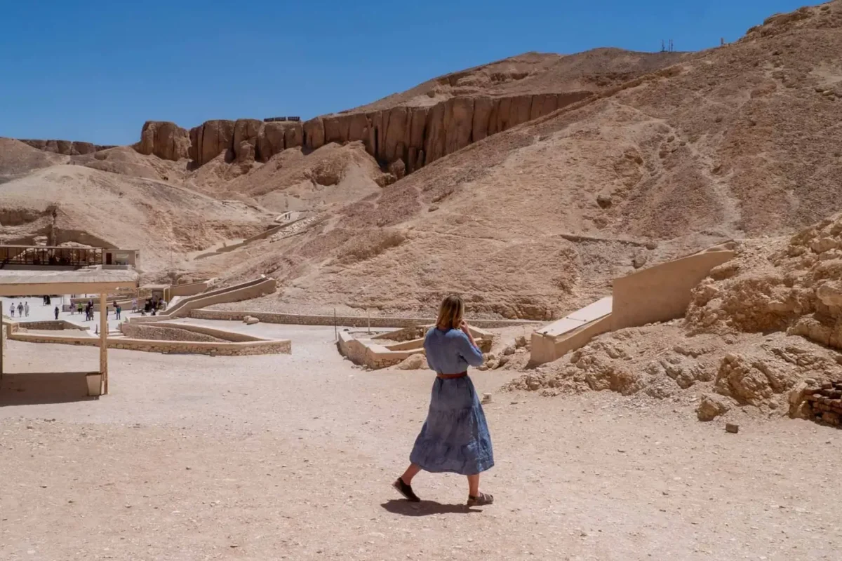 A visitor walking the path between tomb entrances at the Valley of the Kings, the pyramid-shaped peak behind