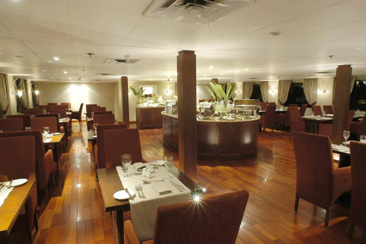 The restaurant on the MS Alexander the Great Nile cruise, tables laid on a polished wood floor with the buffet counter at the far end