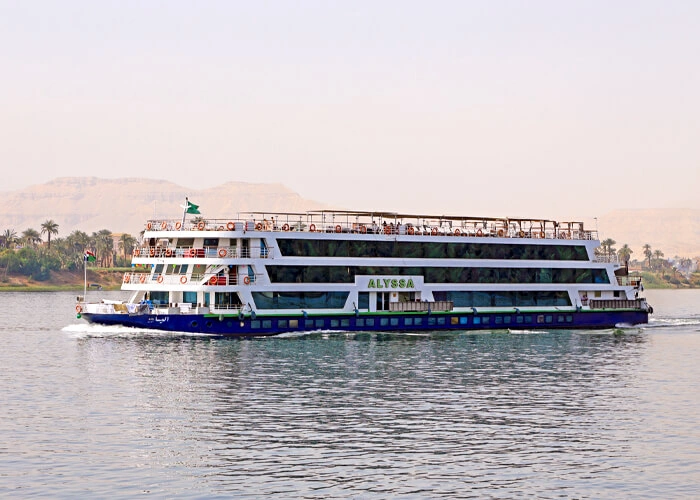 The Alyssa Nile cruise ship on the water with its name along the hull, the Theban hills rising behind