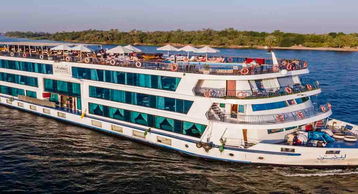 The MS Amwaj Living Stone Nile cruise ship seen from the bow quarter on the Nile, guests along the sun deck rail