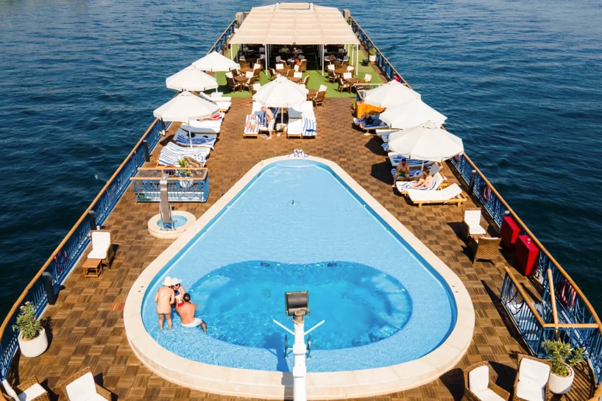 The swimming pool on the MS Amwaj Living Stone Nile cruise sun deck, white parasols and loungers running down both sides