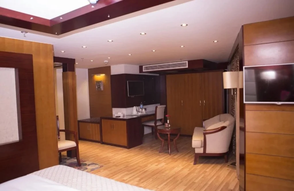 A suite on the Blue Shadow Nile cruise with wood-panelled walls, a desk and mirror, an armchair and a wall-mounted television