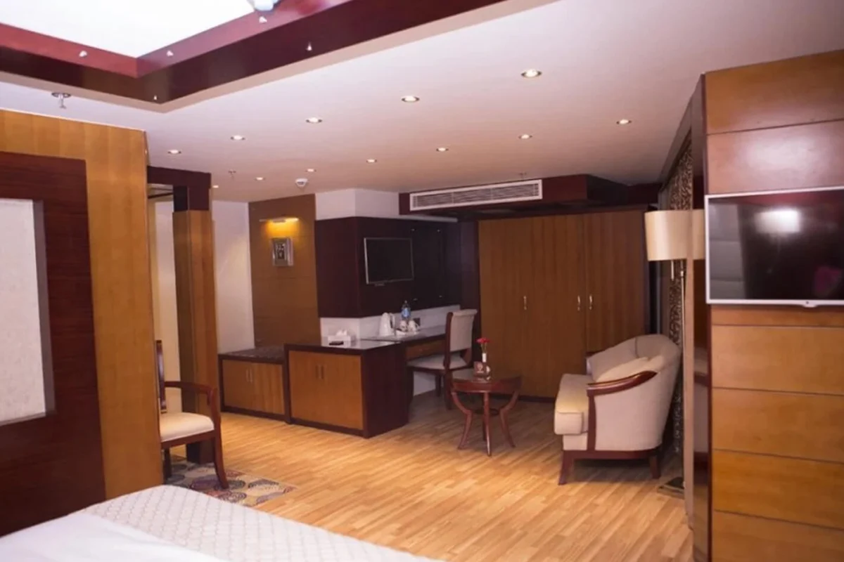 A suite on the Blue Shadow Nile cruise with wood-panelled walls, a desk and mirror, an armchair and a wall-mounted television