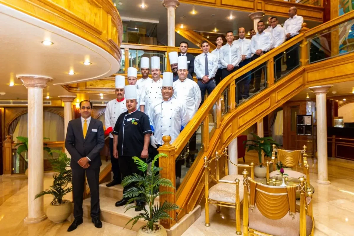 The crew of the Chateau Lafayette Nile cruise, chefs and officers in uniform, gathered on the ship's curved staircase