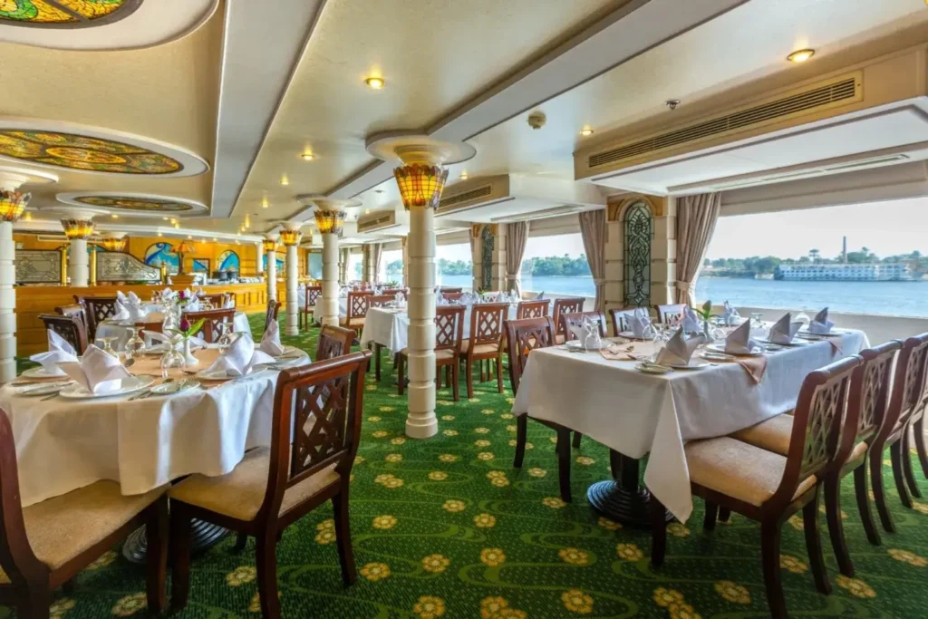 Tables laid for dinner beside the river windows of the Chateau Lafayette Nile cruise restaurant
