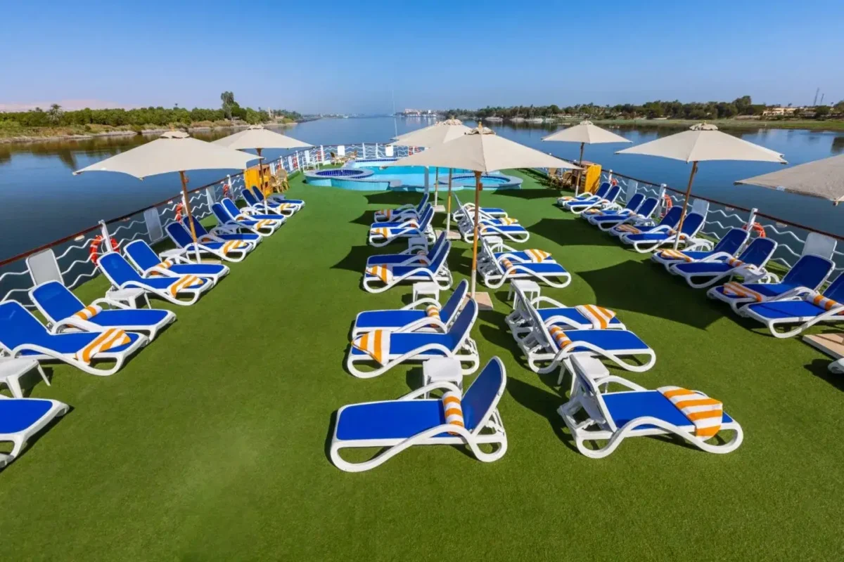 Rows of blue and white loungers with parasols on the Chateau Lafayette Nile cruise sun deck, the riverbank stretching away behind