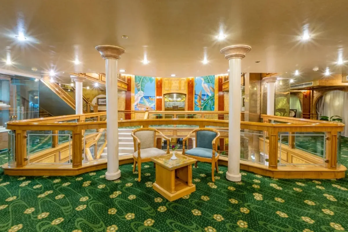 The upper lounge of the Chateau Lafayette Nile cruise, timber balustrades and painted panels around a green patterned floor