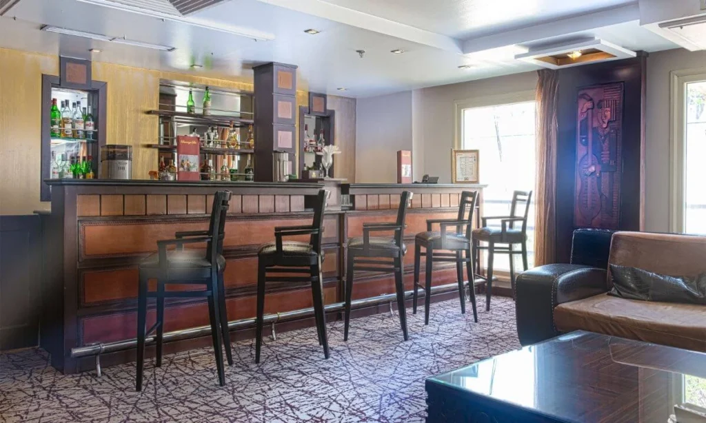 The bar on the Concerto Nile cruise, a row of stools at the counter with bottle shelves behind and leather seating alongside