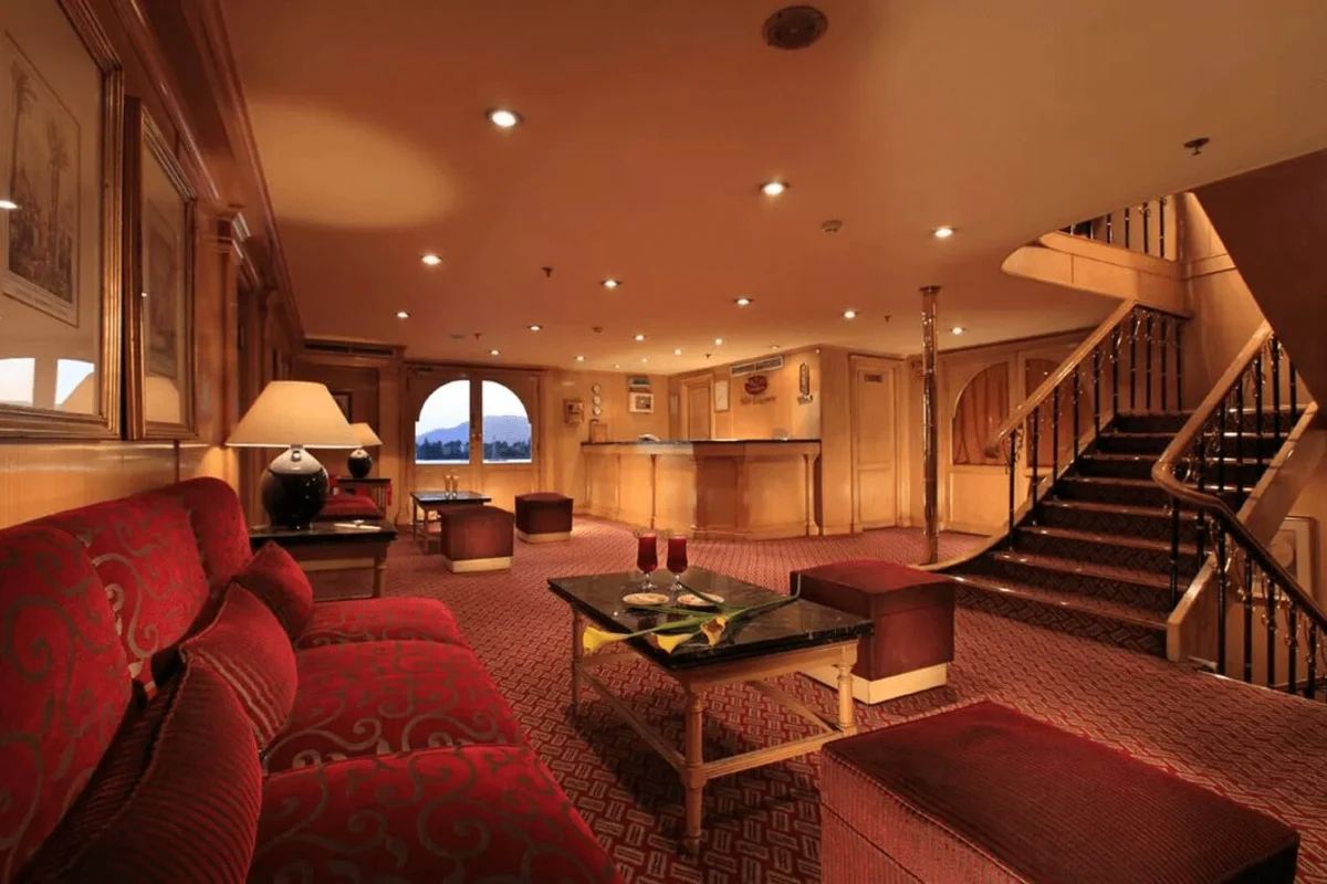 The lobby of the Iberotel Amara Nile cruise, a red sofa and coffee table beside the timber staircase to the upper deck