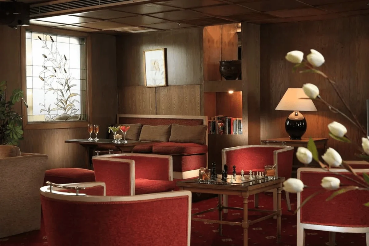 Red tub chairs and a banquette around a low table in the Iberotel Amara Nile cruise lounge, white tulips in the foreground