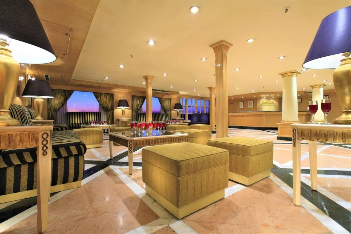 The lounge on the Iberotel Crown Emperor Nile cruise, cream ottomans and striped armchairs on a marble floor between lit columns