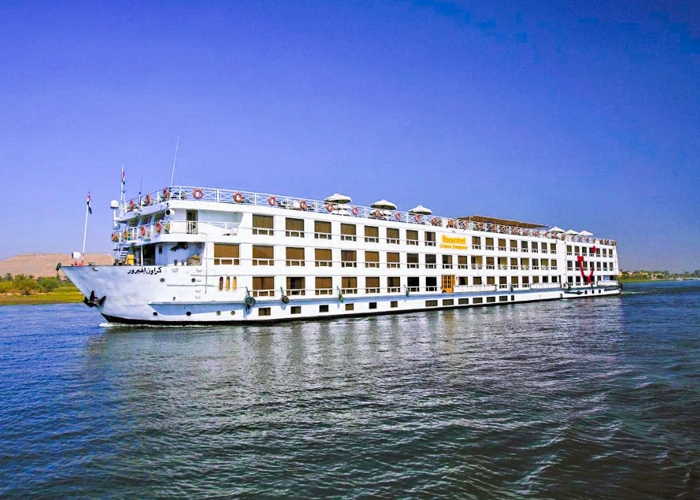 The Iberotel Crown Emperor Nile cruise ship on the Nile seen from the bow quarter, sun umbrellas along the top deck