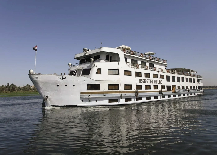 The Iberotel Helio Nile cruise ship on the Nile, its name lettered along the upper deck and an Egyptian flag at the bow