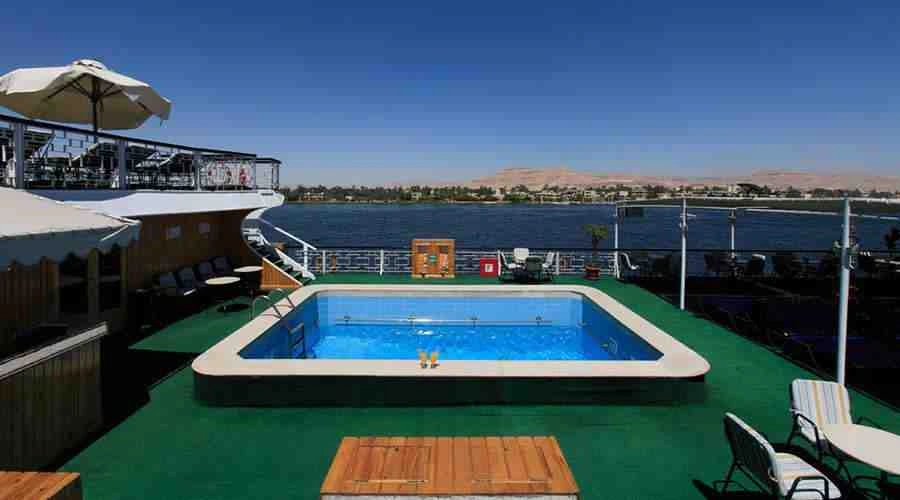 The swimming pool on the Iberotel Helio Nile cruise sun deck, a timber platform beside it and the river stretching away