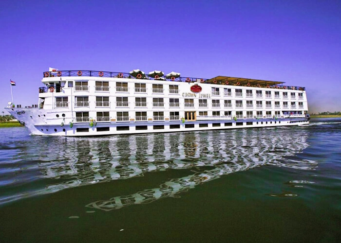 The Jaz Crown Jewel Nile cruise ship on the Nile seen from the bow quarter, an Egyptian flag flying at the stem
