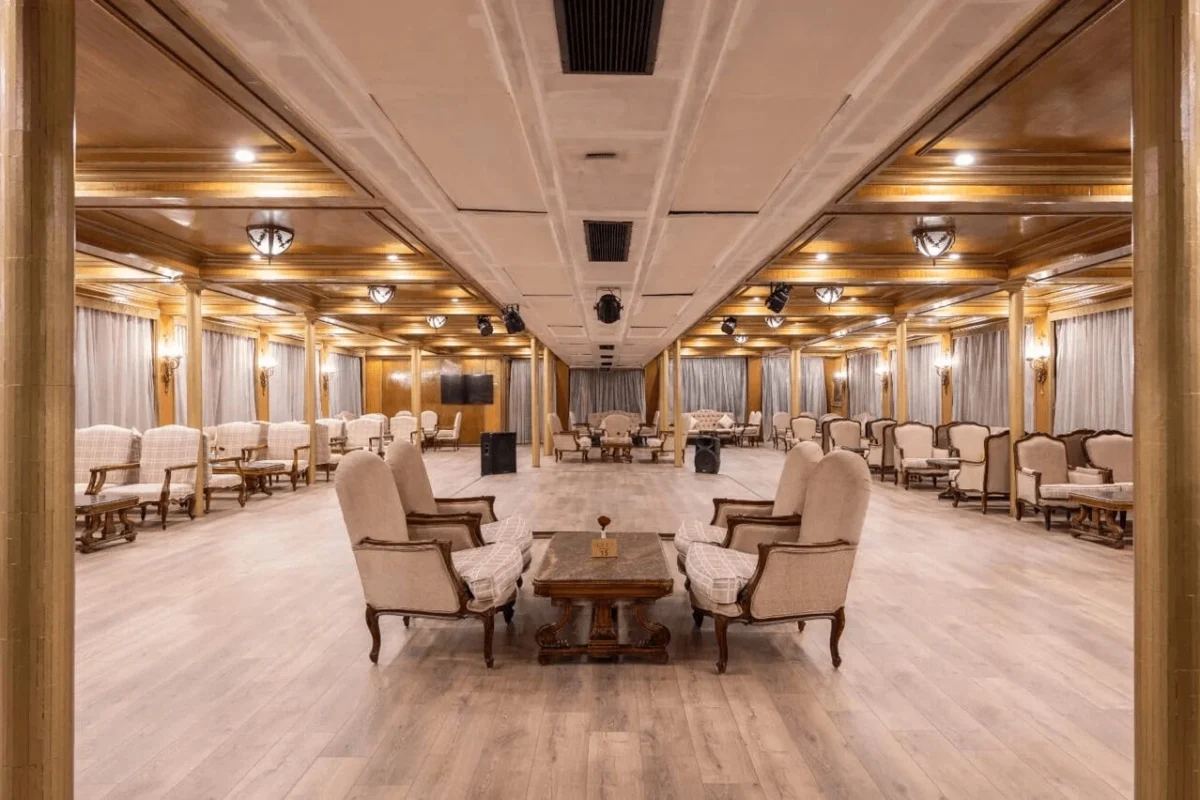 The lounge on the Kleos Nile cruise, cream armchairs in pairs on a pale timber floor beneath a panelled ceiling