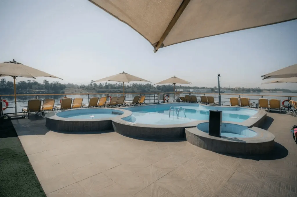 The swimming pool and round jacuzzi on the Lady Carol Nile cruise sun deck, parasols shading the loungers along the rail