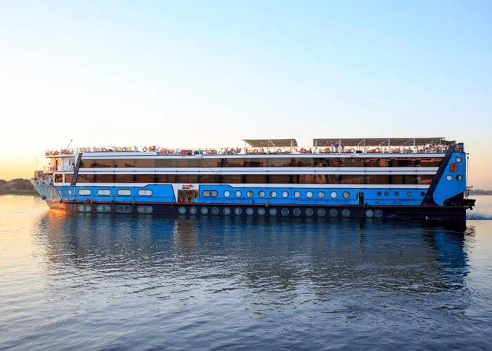 The Lady Mary Nile cruise ship on the Nile at sunrise, its blue and white hull reflected in still water