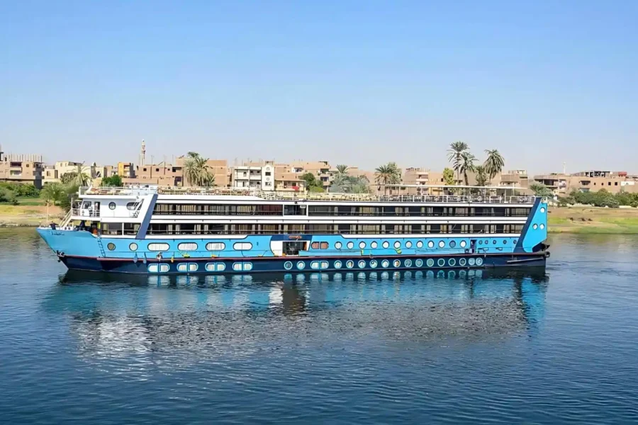 The Magic I Nile cruise ship on the Nile with its bright blue hull, a riverside town behind