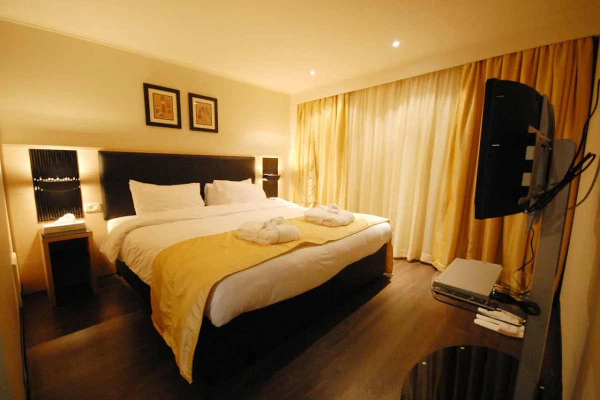 A double cabin on the Moon Dance Nile cruise with a gold throw across the bed and gold curtains at the window
