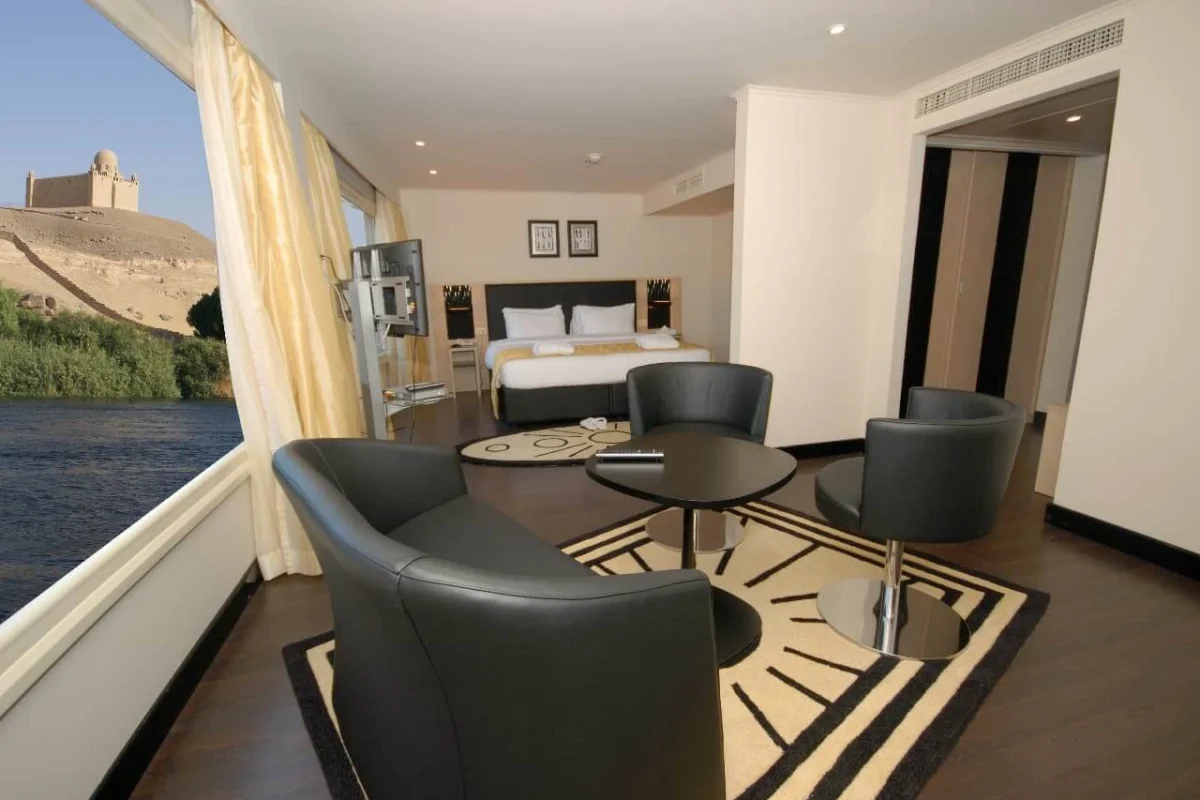 The sitting area of a suite on the Moon Dance Nile cruise, black leather chairs at a round table beside a window onto the Nile