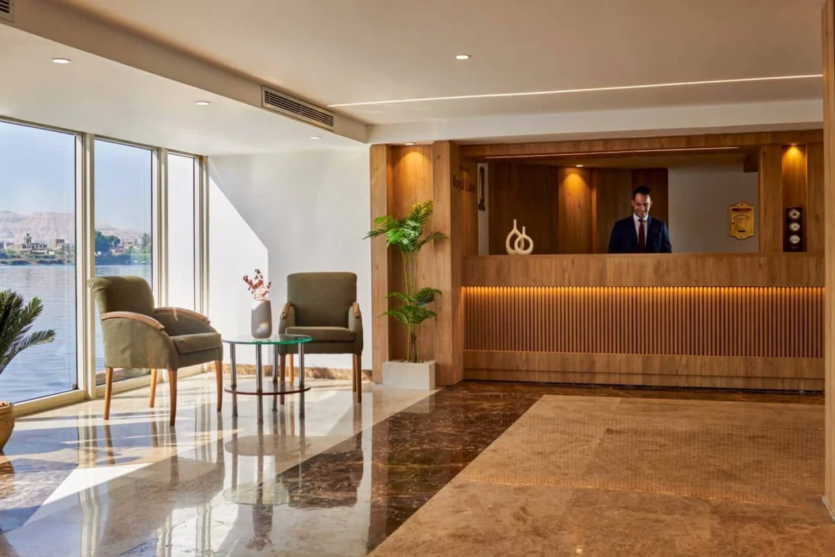 The reception of the Movenpick Royal Lotus Nile cruise, a timber desk on a marble floor with armchairs at the river window