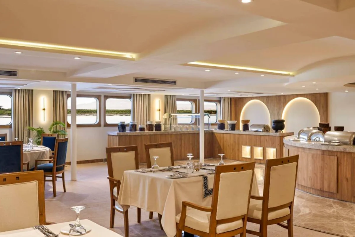 The restaurant on the Movenpick Royal Lotus Nile cruise, tables laid beside the buffet counter with windows along both sides