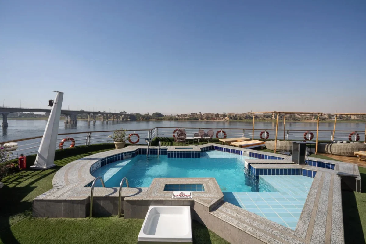 The swimming pool and jacuzzi on the Nile Excellence Nile cruise sun deck, a bridge crossing the river behind